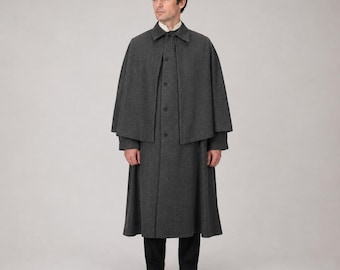 May include: A charcoal gray wool coat with a matching cape. The coat has a button-down front and a long, flowing skirt. The cape is short and covers the shoulders. The person is wearing a white collared shirt and black pants.