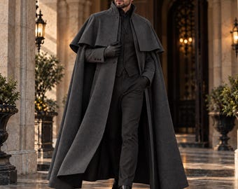 May include: A charcoal gray wool-blend floor-length cape coat featuring a structured collar, a button-front closure, and a layered shoulder design. The garment is worn over a matching charcoal gray vest, dark trousers, and black leather boots.