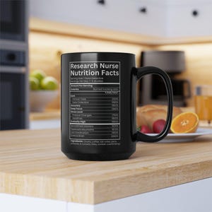 May include: A black ceramic mug featuring a white printed label titled Research Nurse Nutrition Facts. The text lists various professional attributes and percentages, mimicking a nutrition label, including Clinical Trials, Data Collection, and Accuracy.