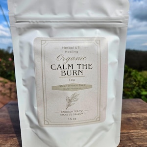 Może przedstawiać: Biała torebka herbaty ziołowej z etykietą z napisem "Organic Calm the Burn Tea". Etykieta zawiera również napis "Wystarczająco herbaty na 1,89 litra" i "42,5 grama".