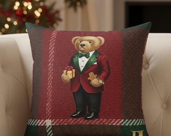 May include: A decorative square pillow with a plaid pattern in red, green, and white. The pillow features a bear wearing a red blazer, black pants, and a green bow tie, holding a gift and a gingerbread man.