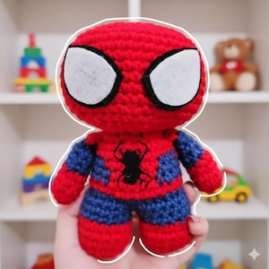 Puede incluir: Muñeco de Spider-Man hecho a mano con ganchillo. El muñeco tiene una cabeza roja con detalles de ojos blancos, un torso rojo con un emblema de araña negro y brazos y piernas azules. Es un juguete suave y de peluche.