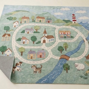 May include: A rectangular rug with a town map design. The rug features a road, houses, a church, a lighthouse, and a river. The rug also includes illustrations of a dog, cat, cow, and sheep. The words "TOWN LIBRARY" are visible.