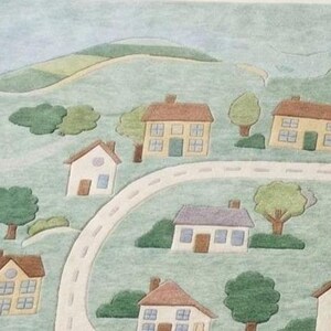 May include: A watercolor-style illustration of a small town with houses, trees, and a winding road. The houses have brown, yellow, and white exteriors with blue and yellow windows. A church with a steeple is also visible.