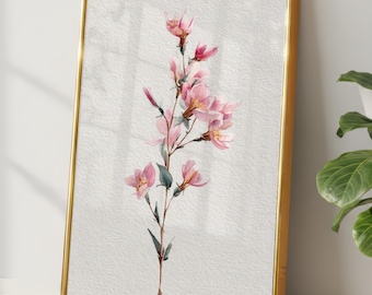 Könnte beinhalten: Ein gerahmter Aquarelldruck mit einem zarten, rosa blühenden Zweig. Das Kunstwerk ist vor einem strukturierten, weißen Hintergrund platziert und in einem goldfarbenen Metallrahmen gefasst. Der Druck lehnt an einer weißen Wand, mit einer Topfpflanze im Hintergrund.