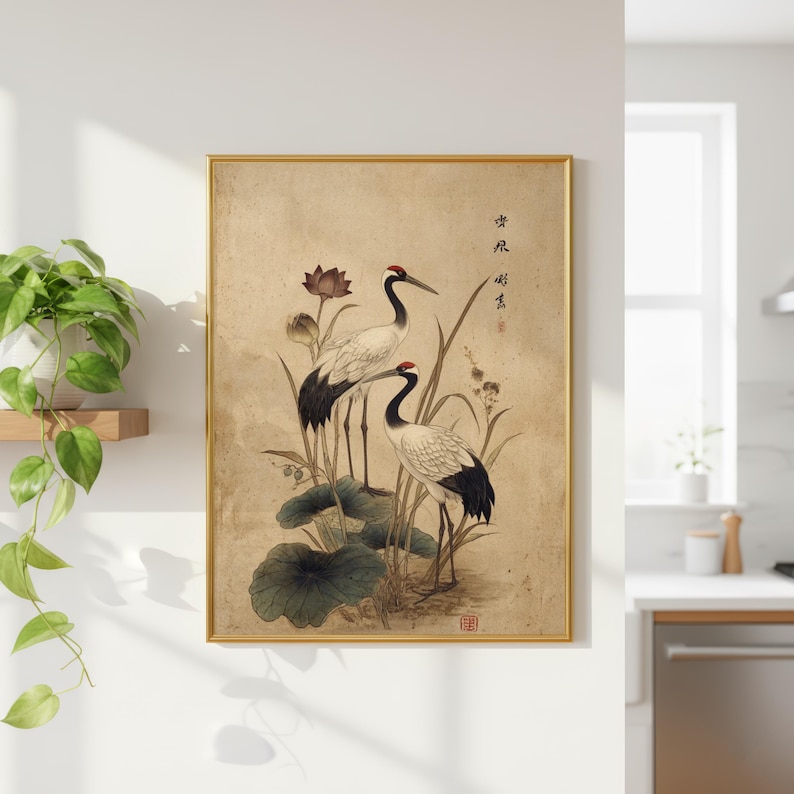 Puede incluir: Impresi&oacute;n art&iacute;stica enmarcada con dos elegantes grullas de plumaje blanco y negro, coronas rojas y largos picos. Las aves se alzan entre hojas de loto y juncos, con caligraf&iacute;a china sobre un fondo beige, dentro de un marco dorado.