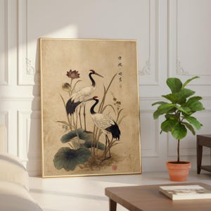 Puede incluir: Impresi&oacute;n art&iacute;stica enmarcada que presenta dos grullas con coronas rojas y plumaje blanco y negro, entre hojas de loto y juncos. La obra de arte tiene un estilo vintage, con caligraf&iacute;a japonesa y un marco dorado.