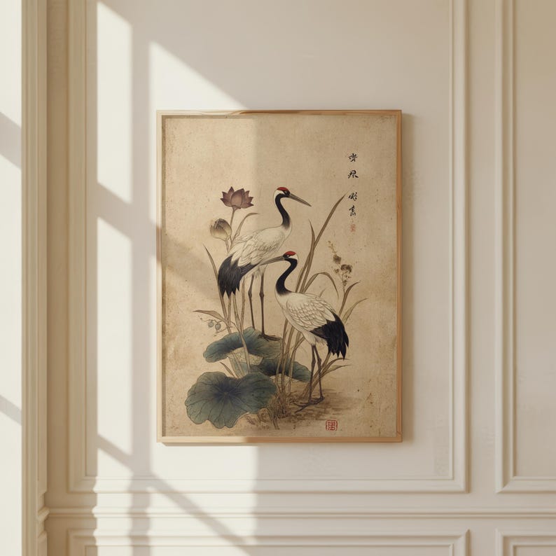 Puede incluir: Una impresi&oacute;n enmarcada con dos grullas japonesas entre hojas y flores de loto. La obra de arte tiene una est&eacute;tica vintage con tonos apagados de beige, negro y rojo. Las grullas son el punto focal, con representaciones detalladas de sus plumas y picos.
