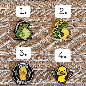 Puede incluir: Cuatro parches bordados. Dos presentan una rana verde sosteniendo pan con el texto "Let's get this bread". Un parche muestra un pato amarillo con cuchillos y el texto "I Choose Violence". El último parche muestra un pato amarillo con cuchillos.