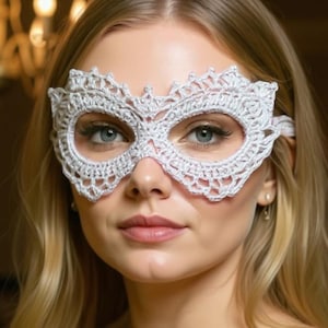 Könnte beinhalten: Eine weiße, gehäkelte Augenmaske mit einem komplizierten floralen Design. Die Maske bedeckt Augen und Nase mit zarten Spitzendetails. Die Maske wird von einer Person mit blondem Haar vor einem verschwommenen Hintergrund getragen.