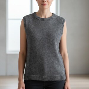 May include: A sleeveless gray knit top with a crew neck and ribbed trim. The top is a solid color and appears to be made of a soft, textured material. The model is wearing black pants.