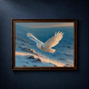 以下が含まれることがあります： 雪景色の上を飛ぶシロフクロウの額装絵画。フクロウは黒い模様のある白い羽を持ち、青い空と雪をかぶった山の背景に配置されています。フレームは濃い茶色です。