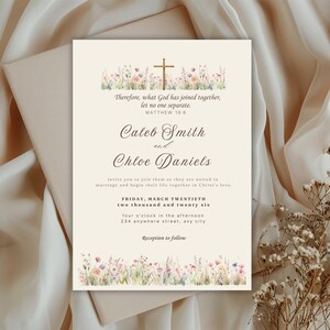 May include: Wedding invitation with floral accents and a gold cross. The text includes the names Caleb Smith and Chloe Daniels, along with the date and time of the ceremony. The invitation is on a cream-colored background.