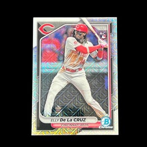 May include: A baseball card featuring Elly De La Cruz of the Cincinnati Reds. The card has a silver and red background with a photo of the player in a batting stance. The text "Elly De La Cruz" and "Cincinnati Reds" are visible.