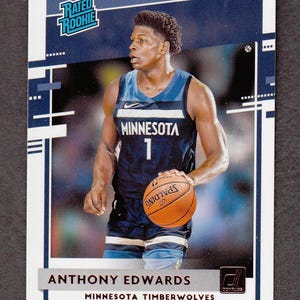 May include: A basketball trading card featuring Anthony Edwards of the Minnesota Timberwolves. The card has a blue and white border with the words "Rated Rookie" at the top. Edwards is wearing a navy blue jersey and holding a Spalding basketball.