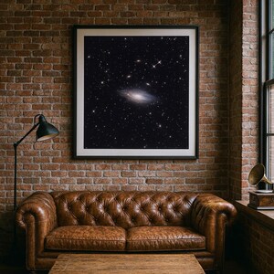 May include: A framed print of a galaxy in a dark, star-filled sky hangs above a brown leather sofa and wooden coffee table. The room has exposed brick walls and a black floor lamp.