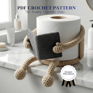 Puede incluir: Un portarrollos de papel higiénico de ganchillo beige con forma de personaje leyendo un libro. El personaje tiene un libro gris y sostiene un rollo de papel higiénico blanco. El texto "PDF Crochet Pattern" y "The Reading Character Holder" son visibles.