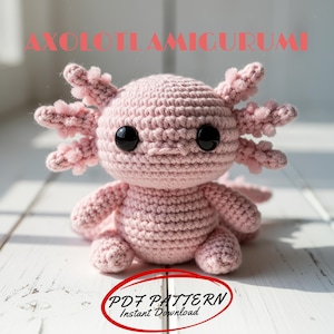 May include: A handmade, light pink amigurumi axolotl with black safety eyes and detailed gills. The crochet axolotl is sitting on a white surface. Text at the top reads "AXOLOTL AMIGURUMI" and text at the bottom reads "PDF PATTERN Instant Download".