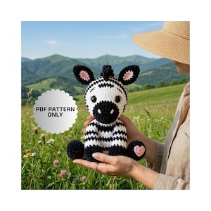 May include: A crocheted zebra toy with black and white stripes, black mane, and pink details on the ears and feet. The text "PDF PATTERN ONLY" is on a white circular label. The zebra is held against a backdrop of green hills and a blue sky.