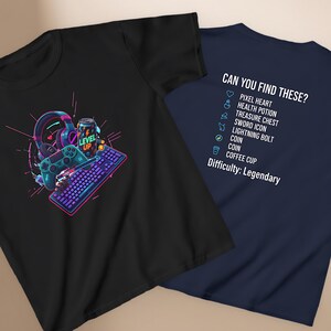 May include: Two t-shirts, one black and one navy blue. The black t-shirt features a colorful graphic of gaming accessories, including a headset, controller, and keyboard. The navy blue t-shirt has the text "CAN YOU FIND THESE?" with a list of gaming-related icons.