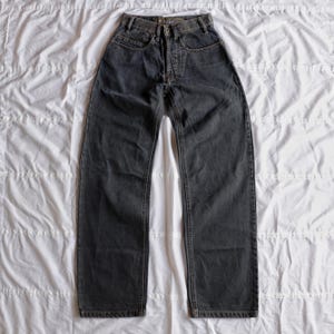 May include: Dark gray denim jeans with a classic five-pocket design. The jeans have a button and zipper closure, belt loops, and a straight leg fit. The fabric appears to be a medium-weight denim.