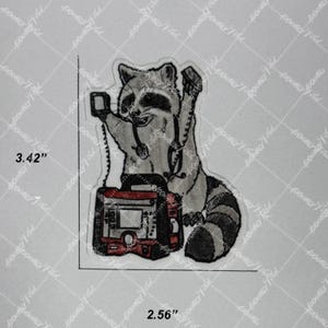 May include: An embroidered patch featuring a raccoon wearing a stethoscope and holding a medical monitor. The patch measures 3.42 inches in height and 2.56 inches in width, with a black, white, and red color scheme.