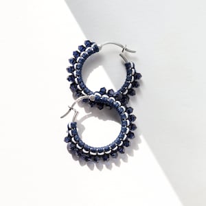 May include: A pair of hoop earrings with a silver metal base and blue and white beaded accents.