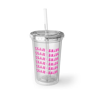 May include: Clear plastic tumbler with a lid and straw. The tumbler is printed with the words "TEAM BRIDE" in pink, repeated vertically. The design includes a pink heart between the words.