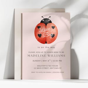 May include: A pink invitation card with a watercolor ladybug design. The ladybug has a red body with black heart-shaped spots and a black head. Text includes "a Love Bug is on the way" and event details.