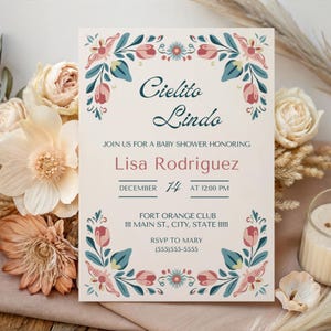 May include: Baby shower invitation with floral border. The invitation features the words "Cielito Lindo" in a script font, along with the name "Lisa Rodriguez" and event details. The design includes pink, teal, and cream-colored floral elements.