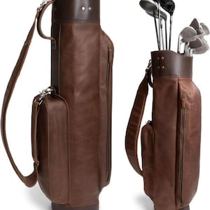 Könnte beinhalten: Zwei braune Golfbags aus Leder. Einer ist leer, der andere enthält Golfschläger. Beide Taschen haben einen dunkelbraunen oberen und unteren Teil, eine Seitentasche und einen Schultergurt. Die Taschen sind aus reichhaltigem, strukturiertem Leder gefertigt.