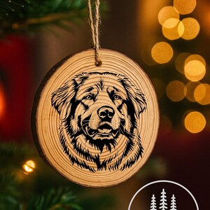 Könnte beinhalten: Runder Weihnachtsbaumschmuck aus Holz mit einem detaillierten Schwarz-Weiß-Porträt eines Hundes. Der Schmuck hat eine natürliche Holzmaserung und eine Schlaufe aus Juteschnur zum Aufhängen. Der Hintergrund ist verschwommen mit Weihnachtsbeleuchtung.