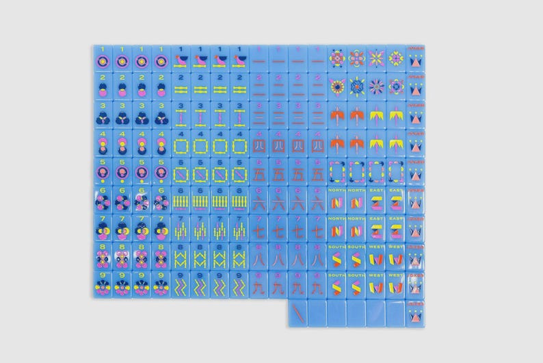 May include: A complete set of light blue mahjong tiles arranged in a grid. Each tile features colorful graphic illustrations, including numbers, Chinese characters, directional symbols, and floral patterns in shades of pink, yellow, and dark blue.