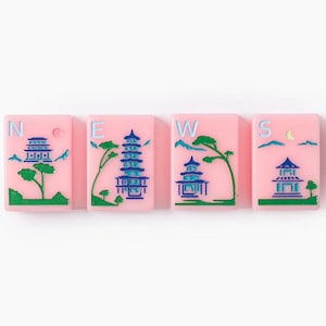Puede incluir: Cuatro fichas de mahjong rectangulares de color rosa dispuestas horizontalmente. Cada ficha presenta un grabado azul y verde de una pagoda, &aacute;rboles y monta&ntilde;as. Las letras N, E, W y S est&aacute;n impresas en azul claro en cada ficha.