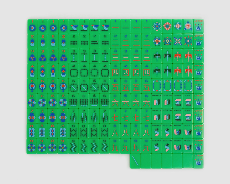 May include: A complete set of bright green mahjong tiles arranged in a grid. The tiles feature various colorful engraved designs including numeric characters, bamboo patterns, circular symbols, directional markers, and floral motifs in blue, red, and pink.