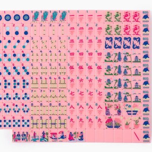 Puede incluir: Un juego completo de fichas de Mahjong rosas dispuestas en una cuadr&iacute;cula. Las fichas presentan dise&ntilde;os en tinta azul, verde y roja que incluyen n&uacute;meros, puntos, bamb&uacute;, dragones, vientos, flores y fichas de Big Joker.