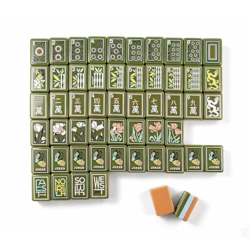 May include: A set of rectangular mahjong tiles in olive green with various printed designs including numbers, Chinese characters, floral patterns, dragon illustrations, and the word Joker. Two additional tiles are placed separately below.