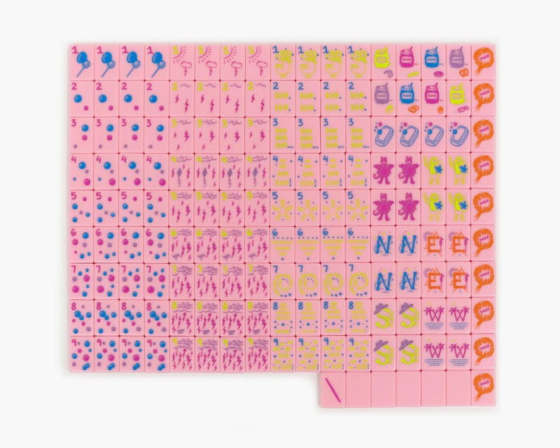 May include: A set of pink mahjong tiles arranged in a grid, featuring various colorful icons including numbers, weather symbols, and cartoon characters. Each tile displays a unique graphic design in blue, yellow, purple, and orange ink.