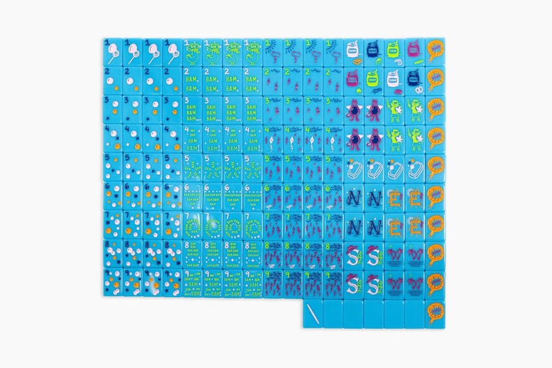May include: A set of rectangular light blue mahjong tiles arranged in a grid. Each tile features colourful graphic illustrations including numbers one through nine, various symbols, cartoon characters, and orange speech bubble icons with text.