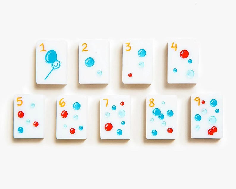 May include: A set of nine rectangular white tiles arranged in two rows, each featuring a yellow numeral from one to nine and a corresponding number of blue and red circular bubble illustrations, with the first tile showing a bubble wand.