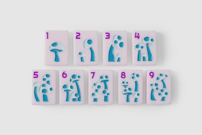 Puede incluir: Un conjunto de nueve baldosas rectangulares de color rosa claro, cada una con un n&uacute;mero morado del uno al nueve y un dise&ntilde;o de hongo azul en relieve. El n&uacute;mero de hongos en cada baldosa corresponde al d&iacute;gito morado en la esquina superior.
