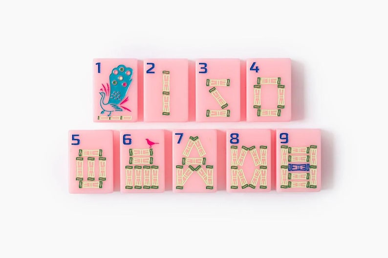 Puede incluir: Un conjunto de nueve fichas de mahjong rectangulares de color rosa dispuestas en dos filas. Cada ficha presenta un n&uacute;mero azul del uno al nueve en la esquina superior izquierda. Las fichas muestran ilustraciones de bamb&uacute;, un pavo real y un ave.