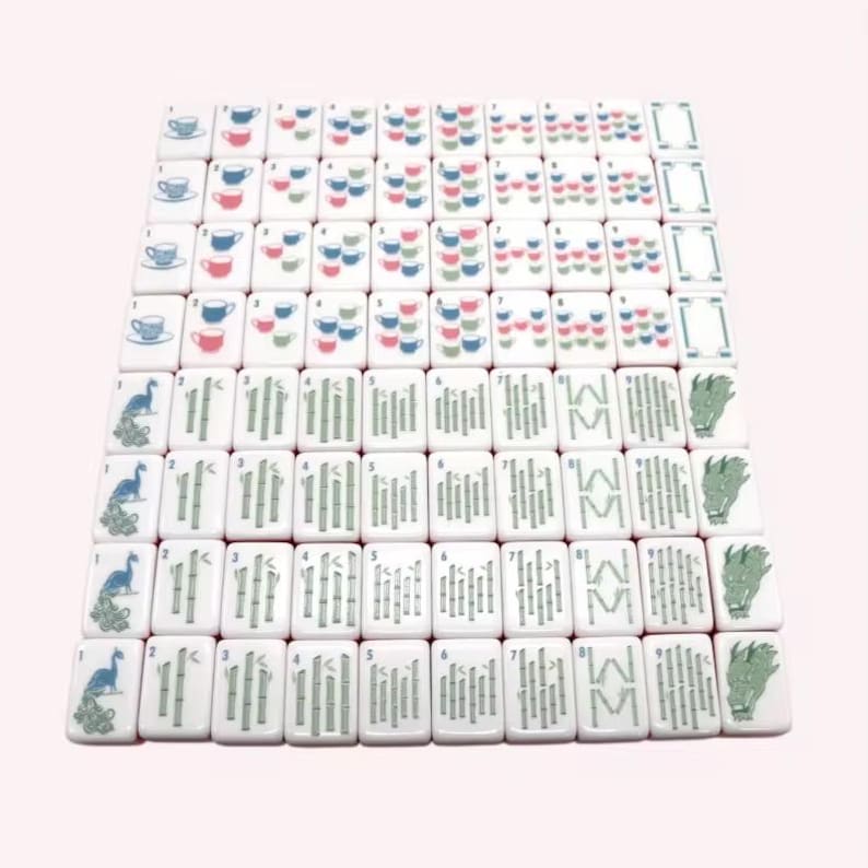 May include: A set of white rectangular mahjong tiles arranged in a grid. The tiles feature various illustrations including blue and pink teacups, green bamboo stalks, blue peacocks, green dragon heads, and numerical markings in the corners.