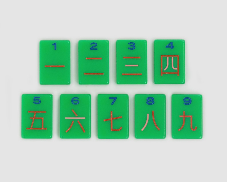 May include: Nine rectangular green tiles arranged in two rows. Each tile features a blue Arabic numeral from 1 to 9 at the top and a corresponding red Chinese character for that number below it. The tiles have a smooth, glossy finish.