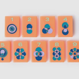 May include: A set of nine rectangular orange tiles, each featuring a unique geometric pattern of overlapping circles in shades of blue, teal, and lavender. Each tile is numbered from one to nine in a light green font, arranged in two rows.