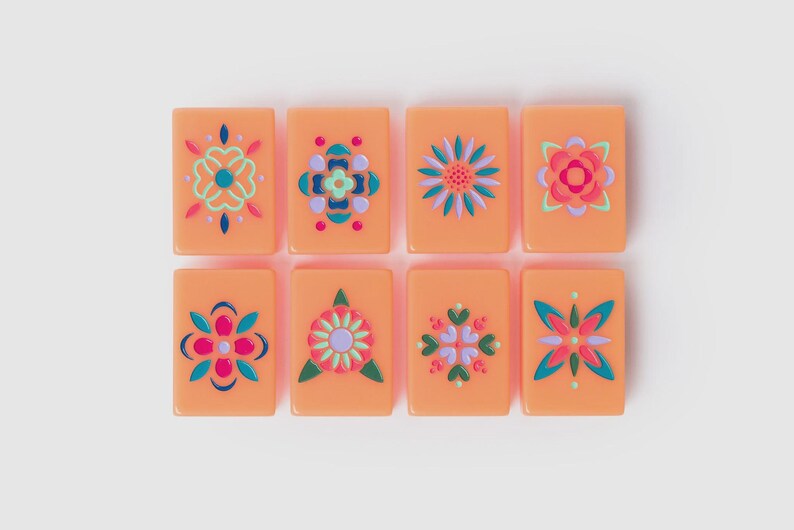 May include: Eight rectangular peach-colored tiles arranged in two rows of four. Each tile features a unique, symmetrical floral or geometric pattern painted in vibrant shades of teal, magenta, lavender, and dark blue, creating a colorful set.
