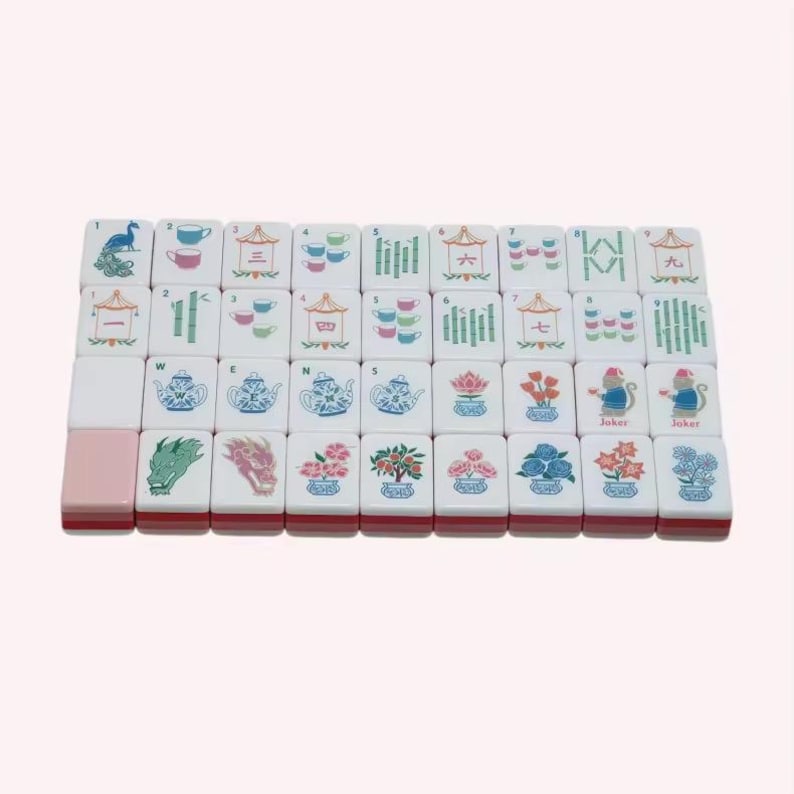 May include: A set of white rectangular mahjong tiles arranged in a grid, featuring colorful illustrations of teapots, teacups, bamboo stalks, flowers, dragons, and Chinese characters. One tile is solid pink, and two tiles are labeled as Joker.
