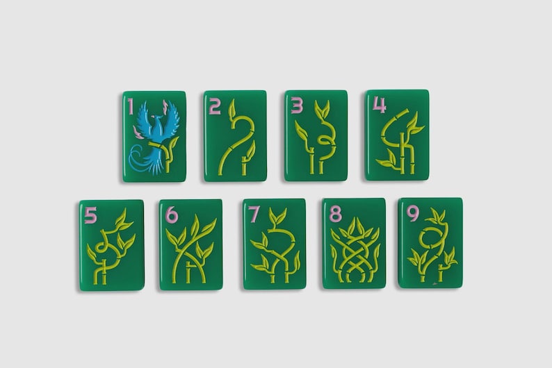 May include: A set of nine rectangular green mahjong tiles arranged in two rows. Each tile features a light pink numeral from one to nine and a yellow bamboo-style graphic, except for the number one tile, which displays a blue phoenix illustration.