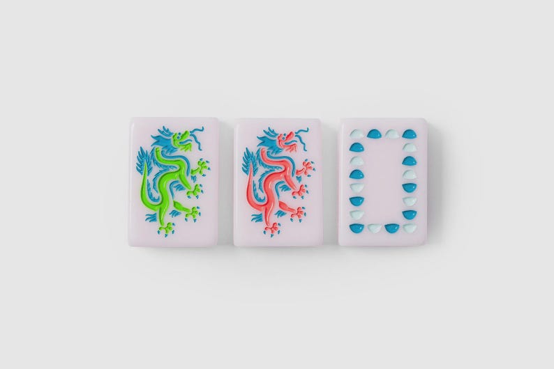 Puede incluir: Tres fichas de mahjong rectangulares con una base de color rosa p&aacute;lido. Dos fichas presentan una ilustraci&oacute;n detallada de un drag&oacute;n, una en verde vibrante y la otra en rojo brillante. La tercera ficha muestra un borde rectangular de semic&iacute;rculos azules.