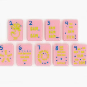 May include: A set of nine rectangular pink tiles, each featuring a blue number from one to nine and yellow text reading BAM. The tiles display various arrangements of the word BAM, small blue stars, and a yellow chicken illustration on the number one tile.